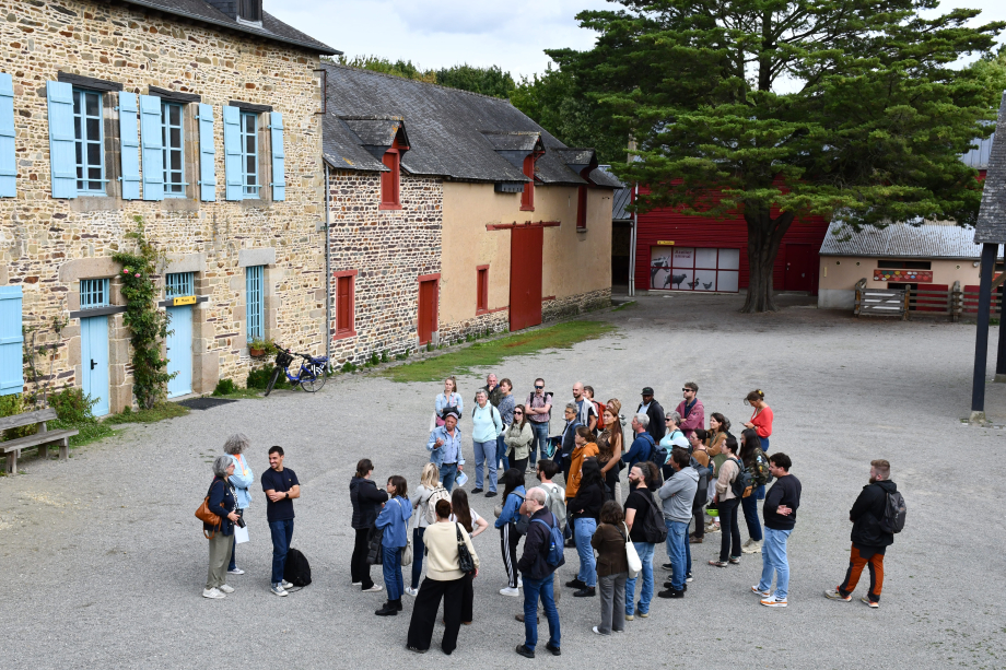 un groupe écoute un guide dans la cours de la ferme